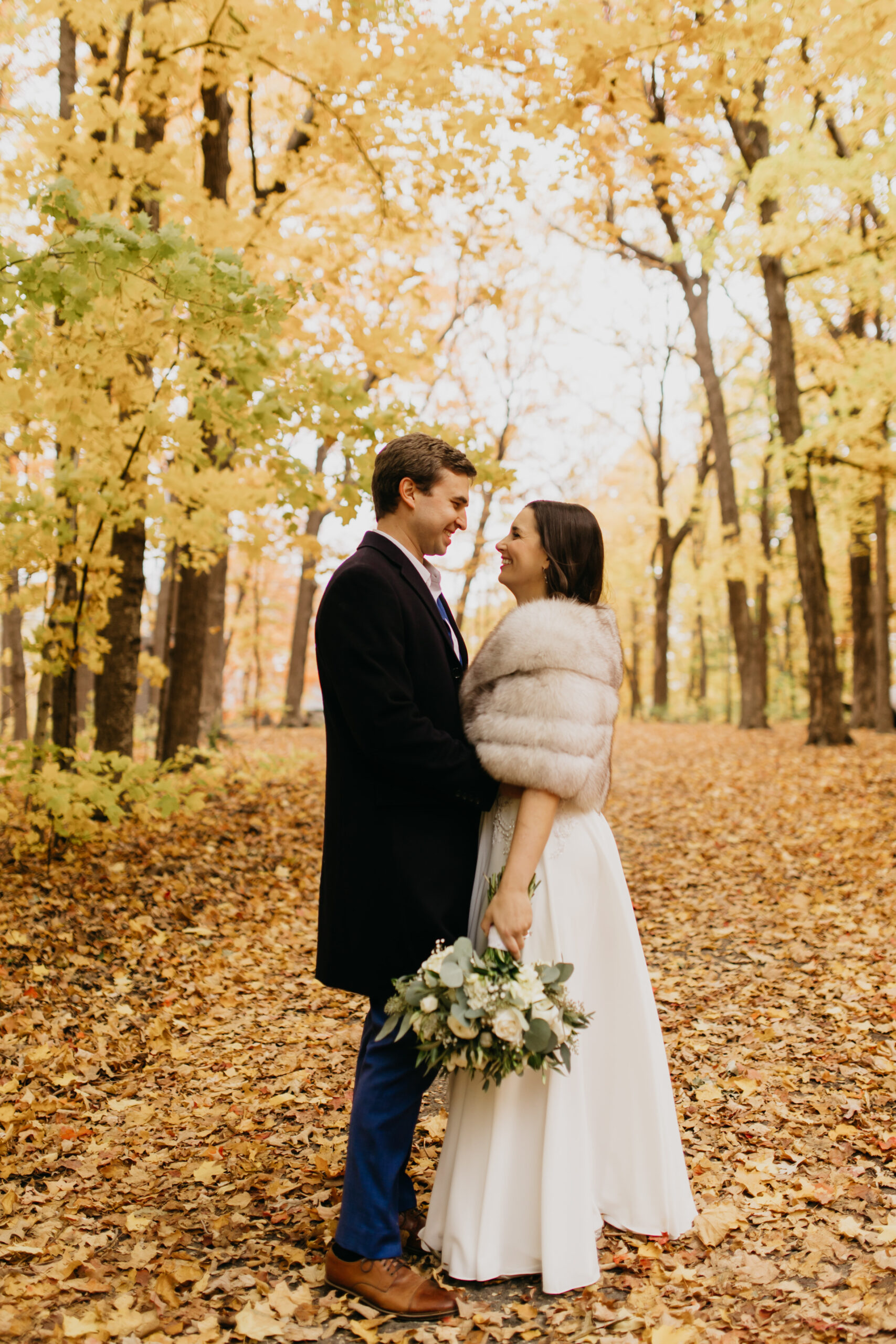 A full body shot of a couple glancing at each other with fall backdrop