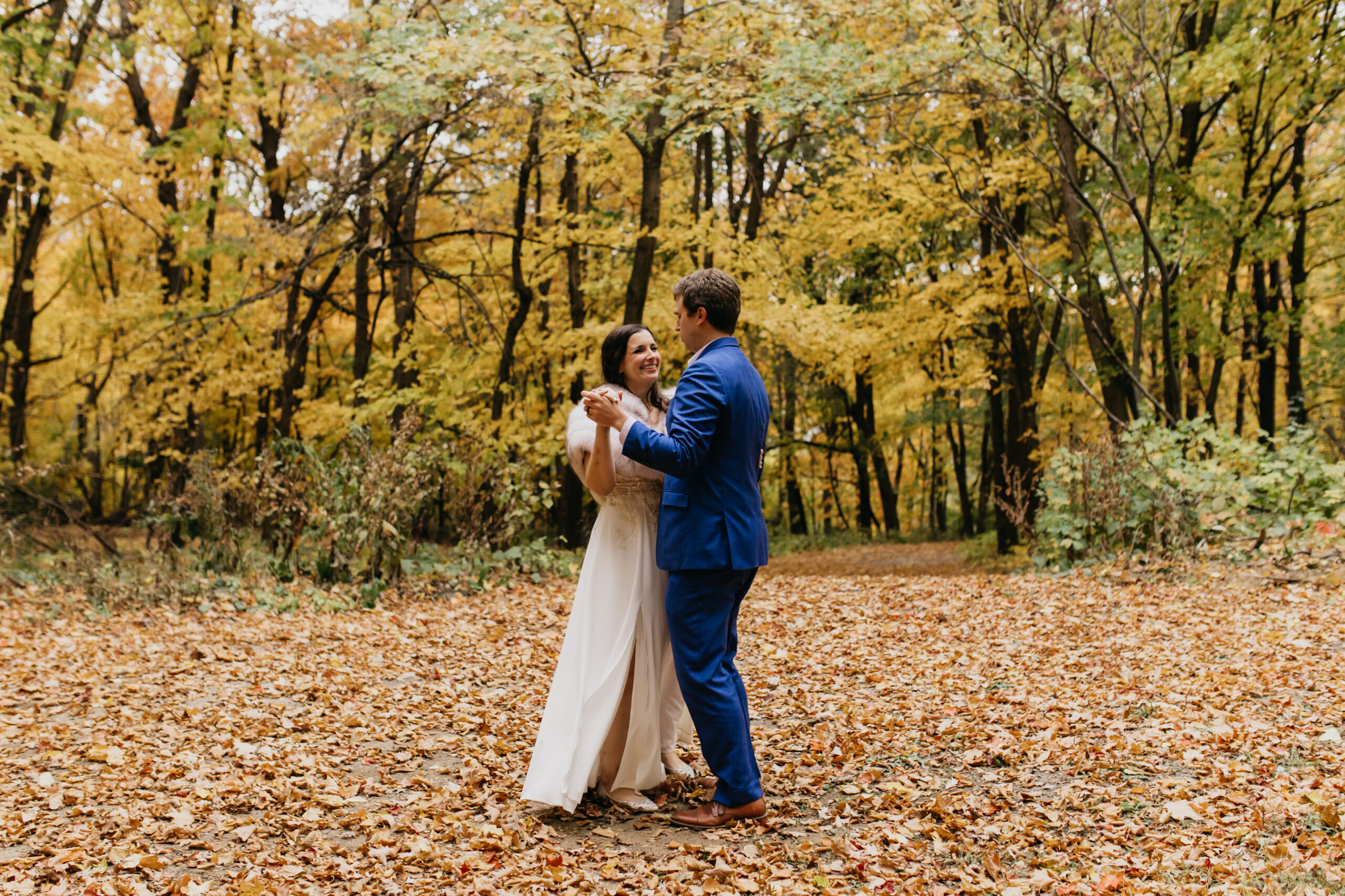 A wedding couple dancing with fall backdrop