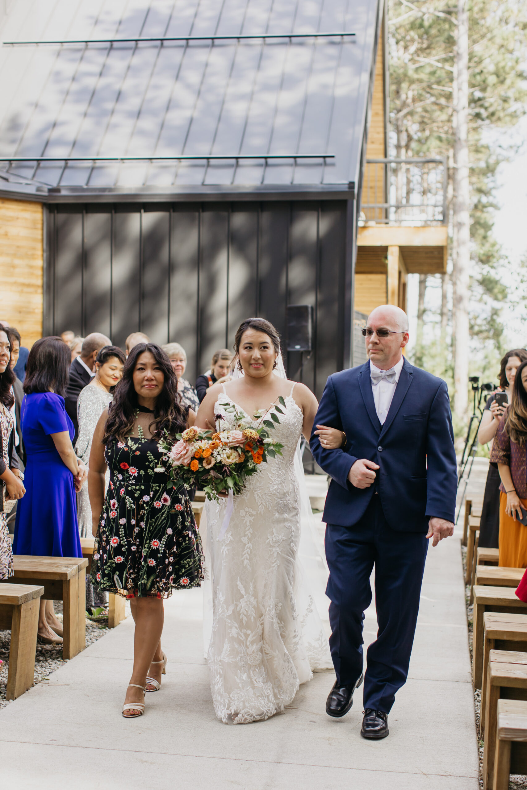 Photo of the bride and her parents walking her down the aisle