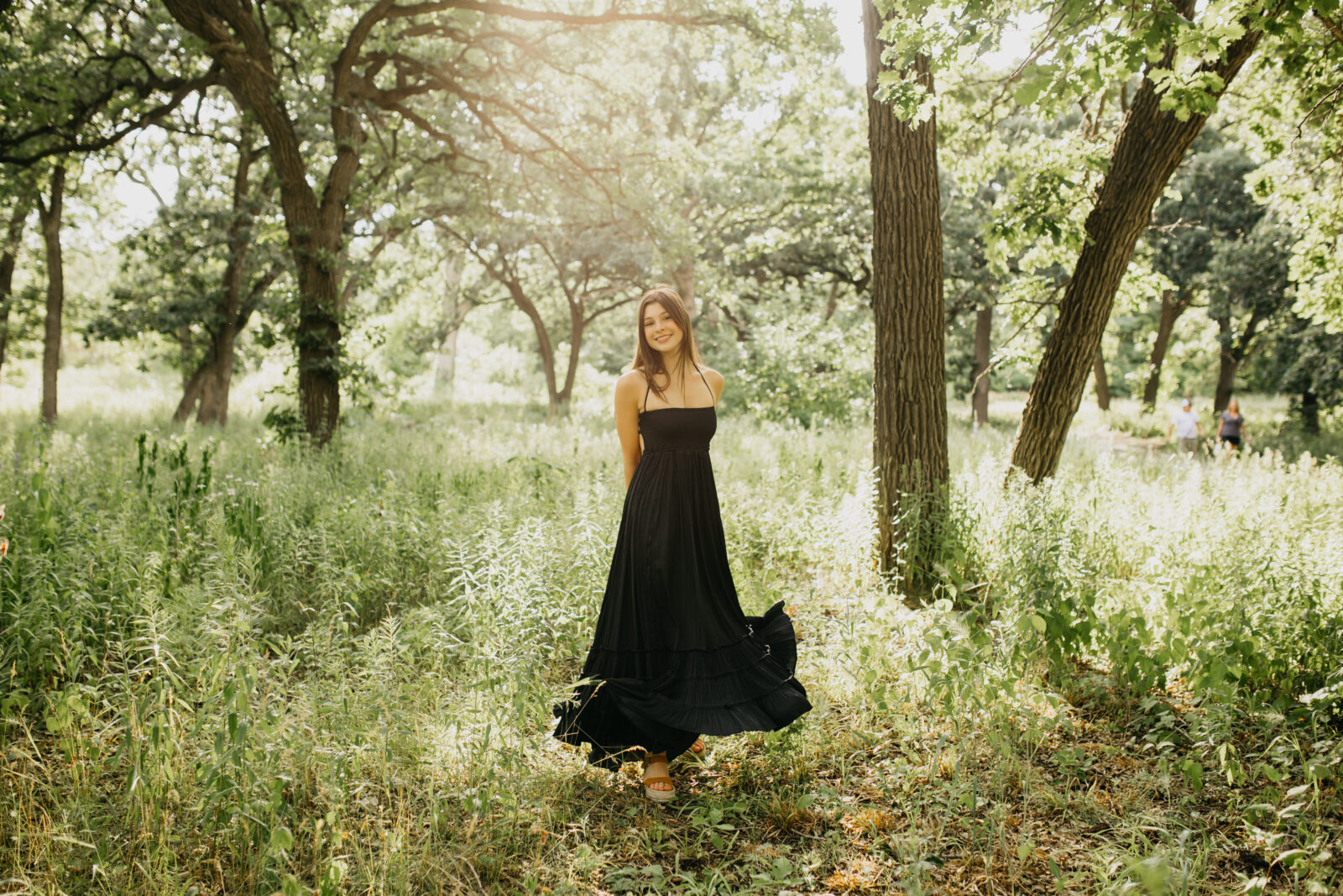 A high school senior wearing a flowy black dress wit the nature as the background