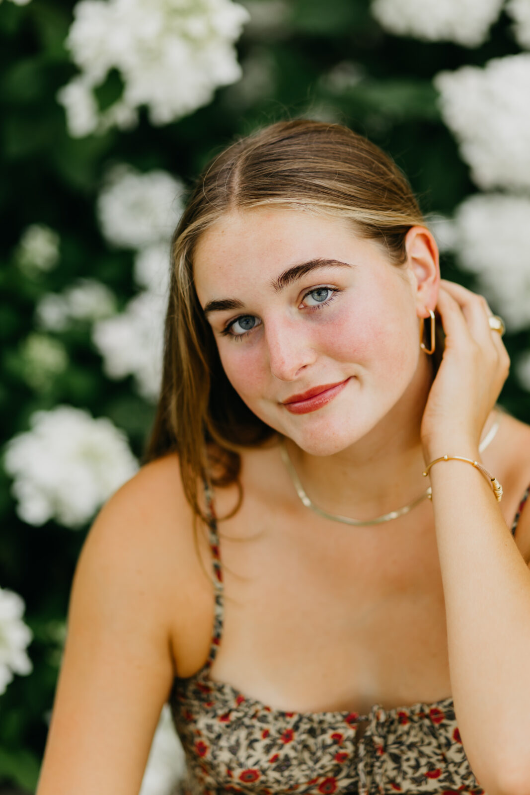 Photo of a senior during her senior shoot against a white floral background