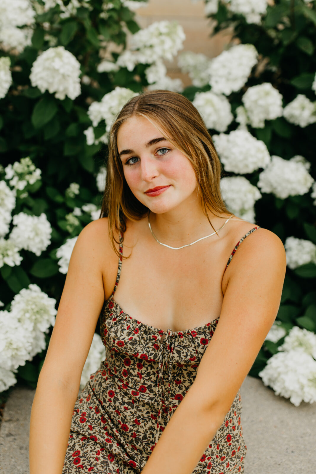 Photo of a senior during her senior shoot against a white floral background