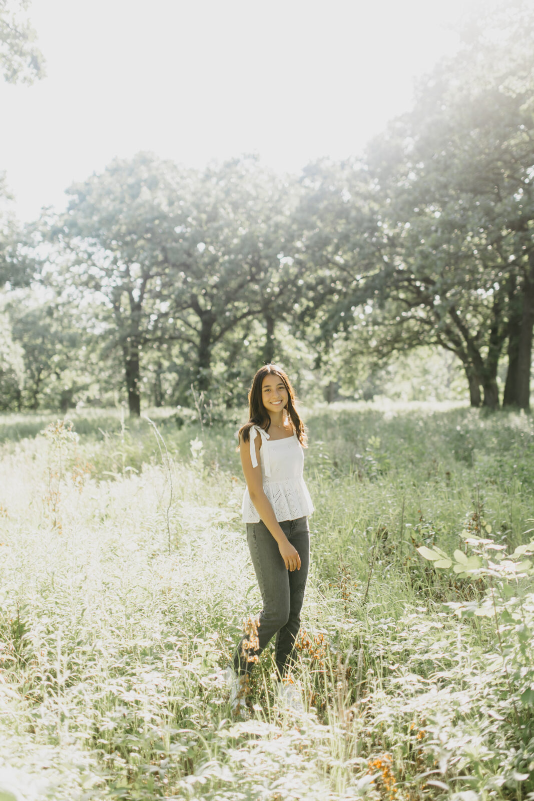 A smiling high school senior captured against a backdrop of nature in a photograph.