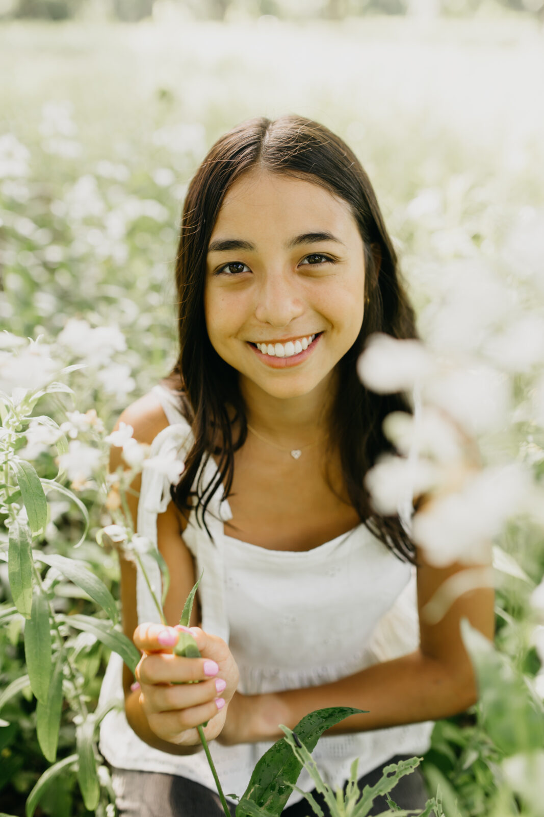 A lovely high school senior being photographed in a field of flowers