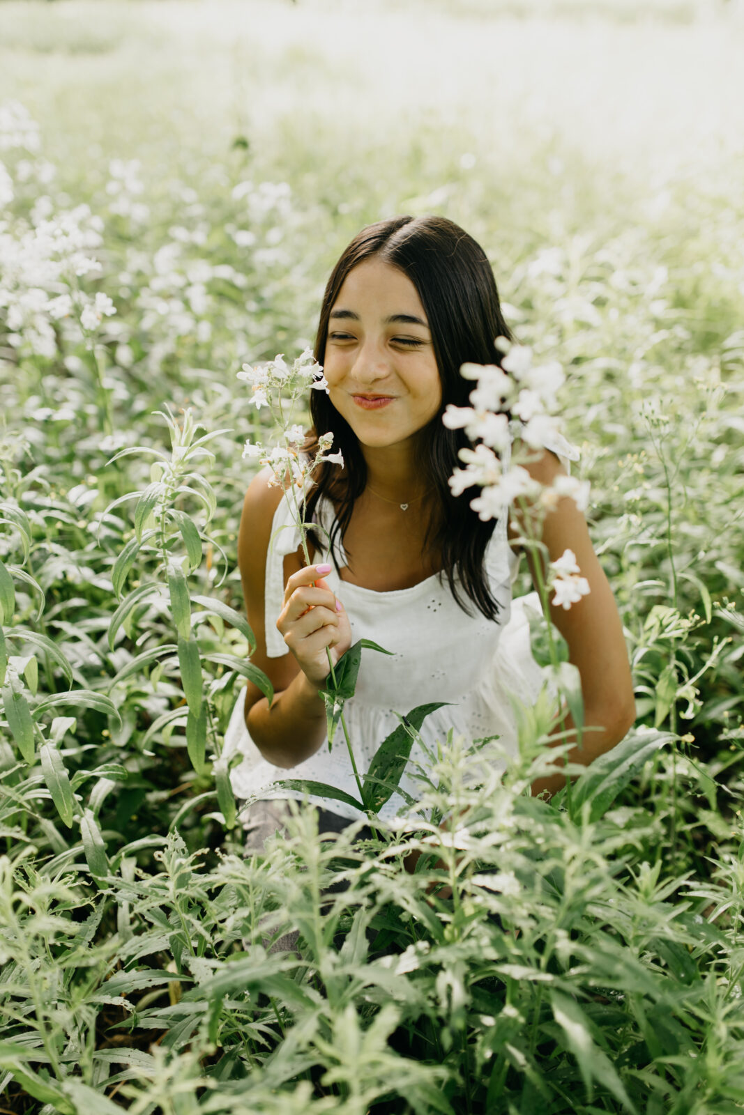 A lovely high school senior being photographed in a field of flowers
