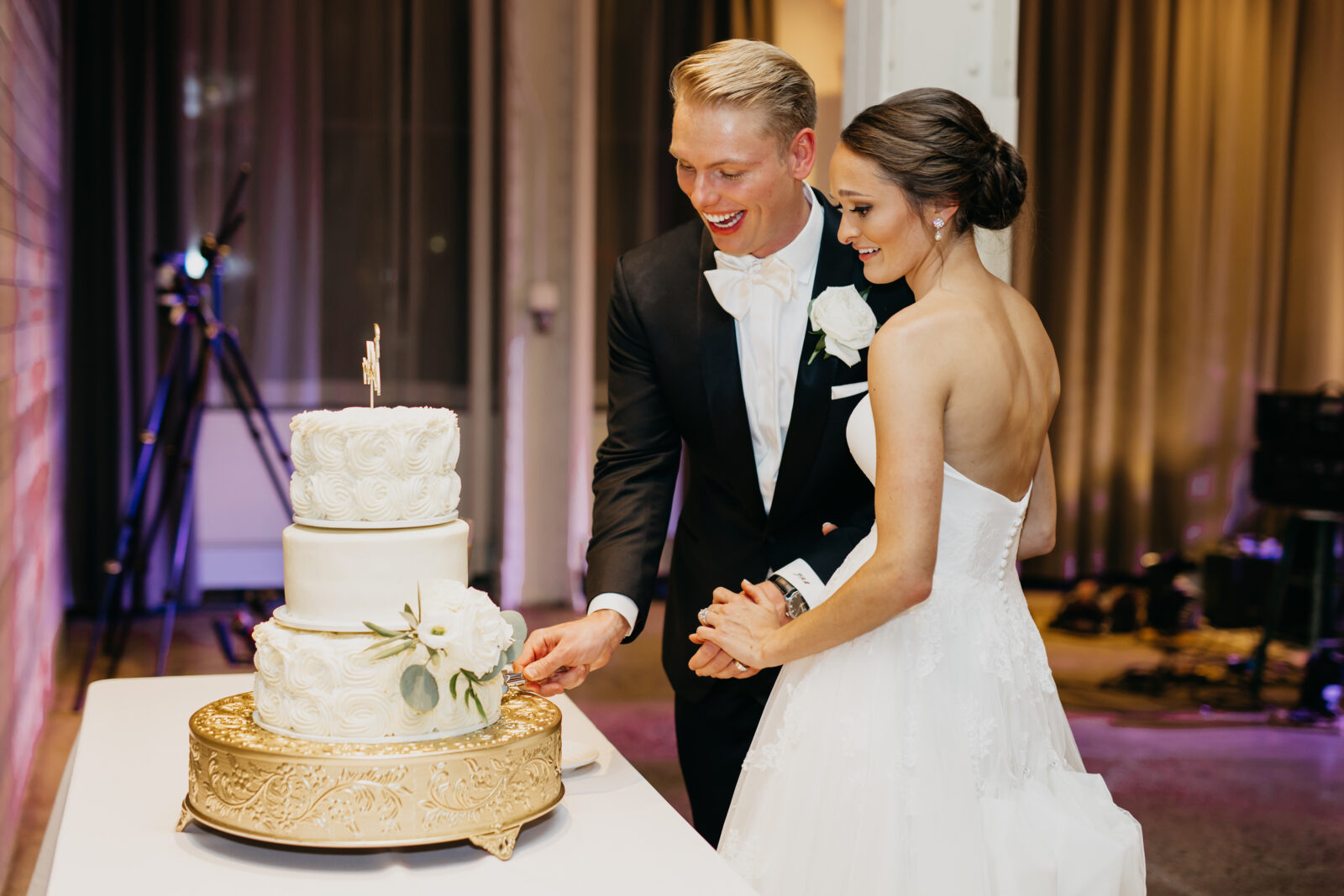 A photo of the bride and groom slicing their first piece of cake as newlyweds.