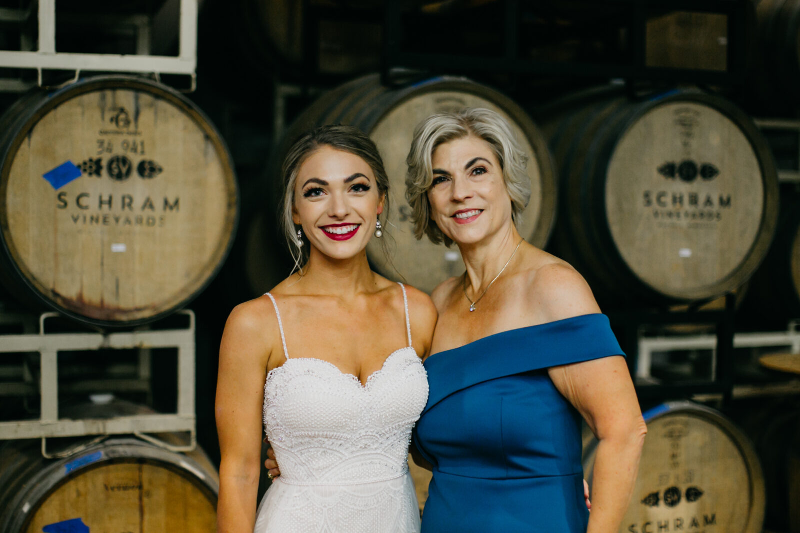 A photo of the bride in white gown and her mom in a aquamarine blue gown during the bride's wedding day at the Schram Vineyards