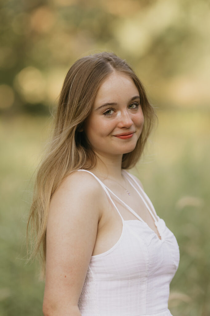 a medium shot of a high school senior in her white dress