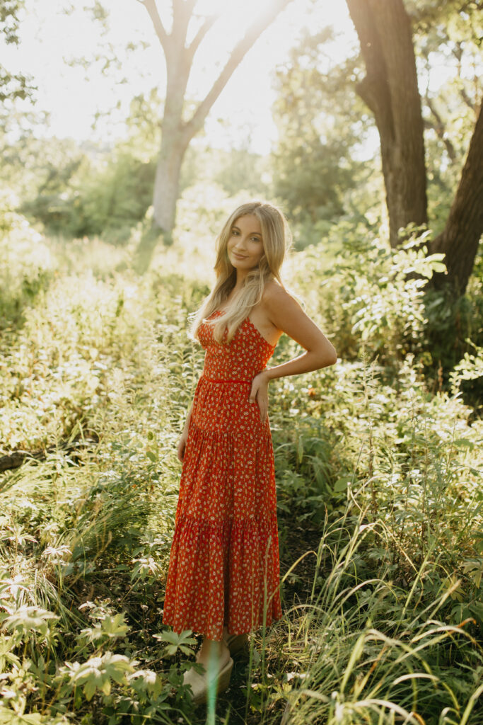 Meryl's high school senior photos taken in a field of greenery, wearing her vibrant red dress