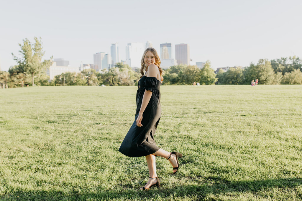 A photo of a Senior wearing a black dress with the city serving as a backdrop of the shoot