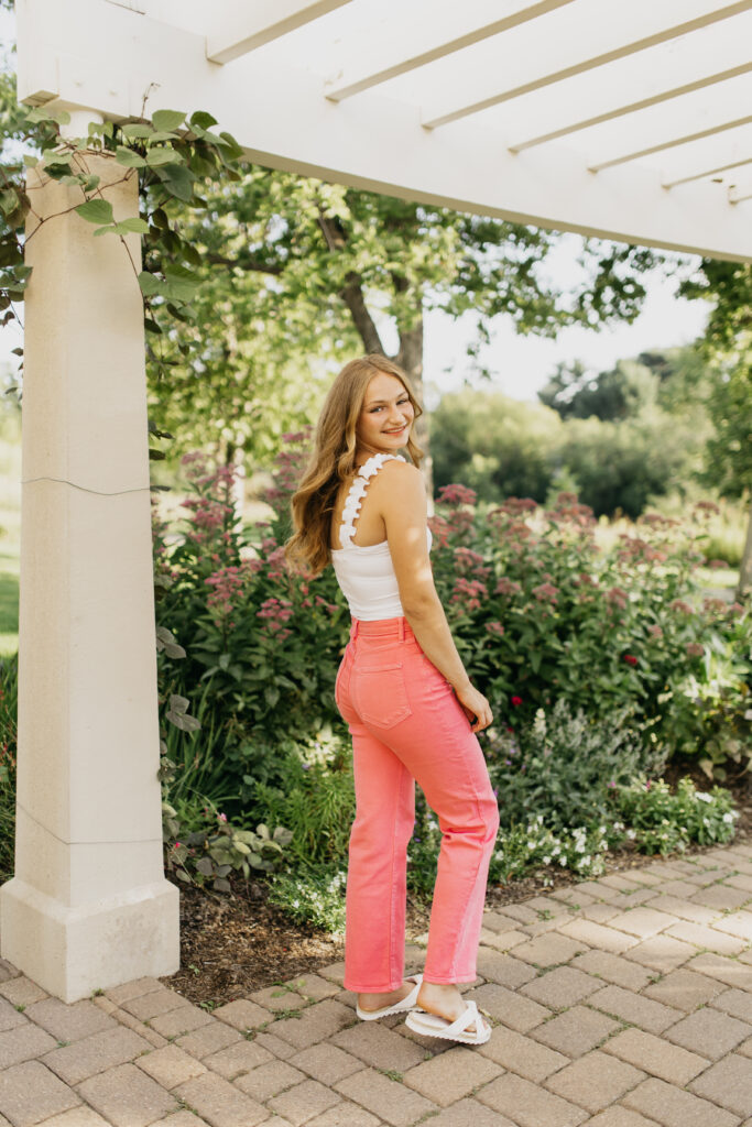 A photo of a senior wearing a white top and pink jeans