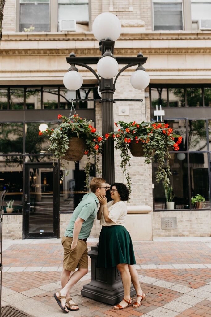 Photo of an engaged couple posing on a lamp post