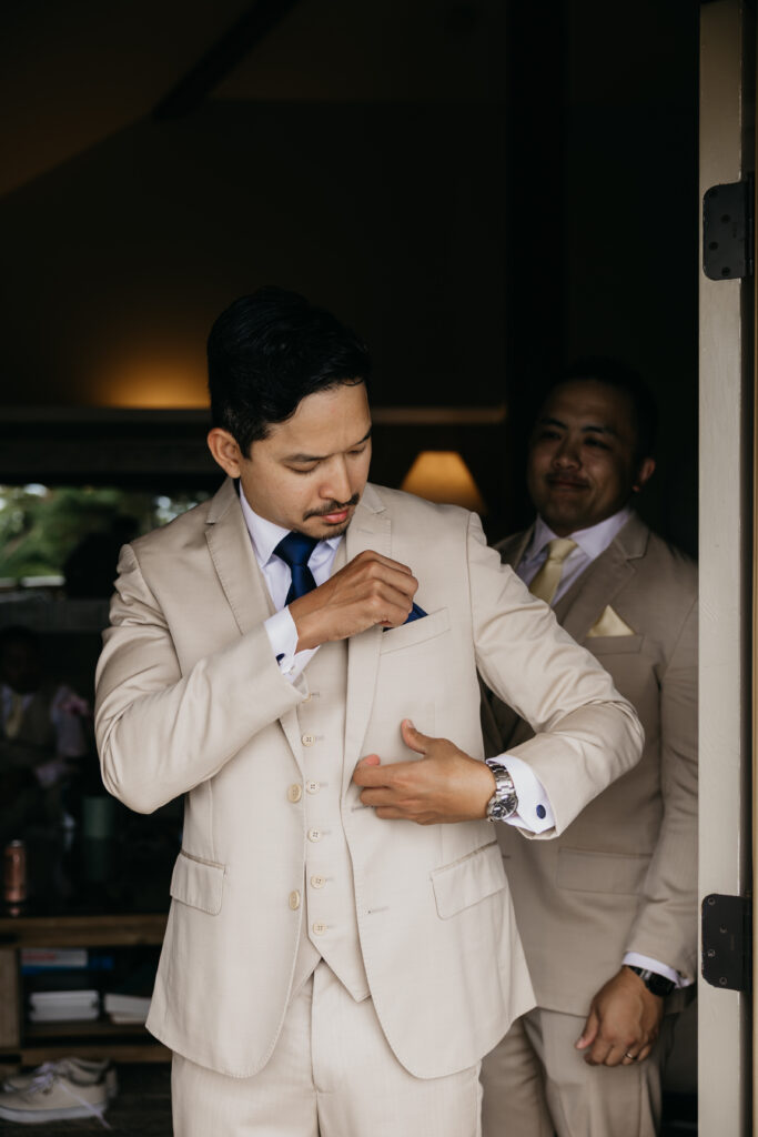 Groom adjusting his suit jacket while getting ready with groomsmen before a Montecito private estate wedding.