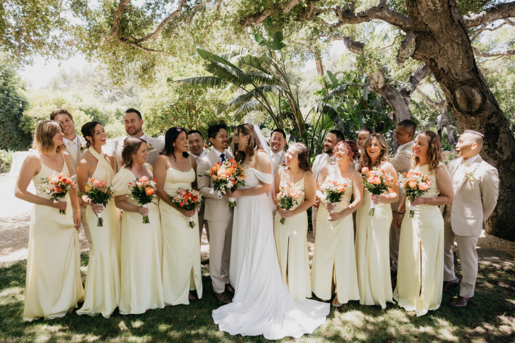 Bride and groom celebrating with their wedding party dressed in pale yellow gowns and tan suits at a Montecito private estate.