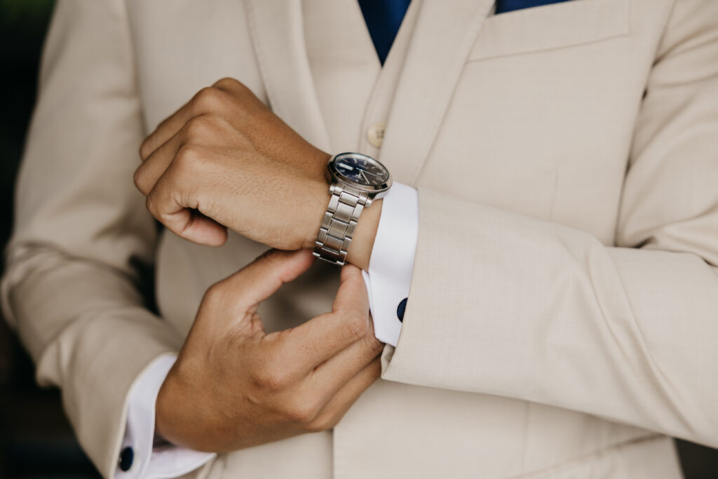 Close-up of groom fastening a silver watch while preparing for his Montecito wedding.