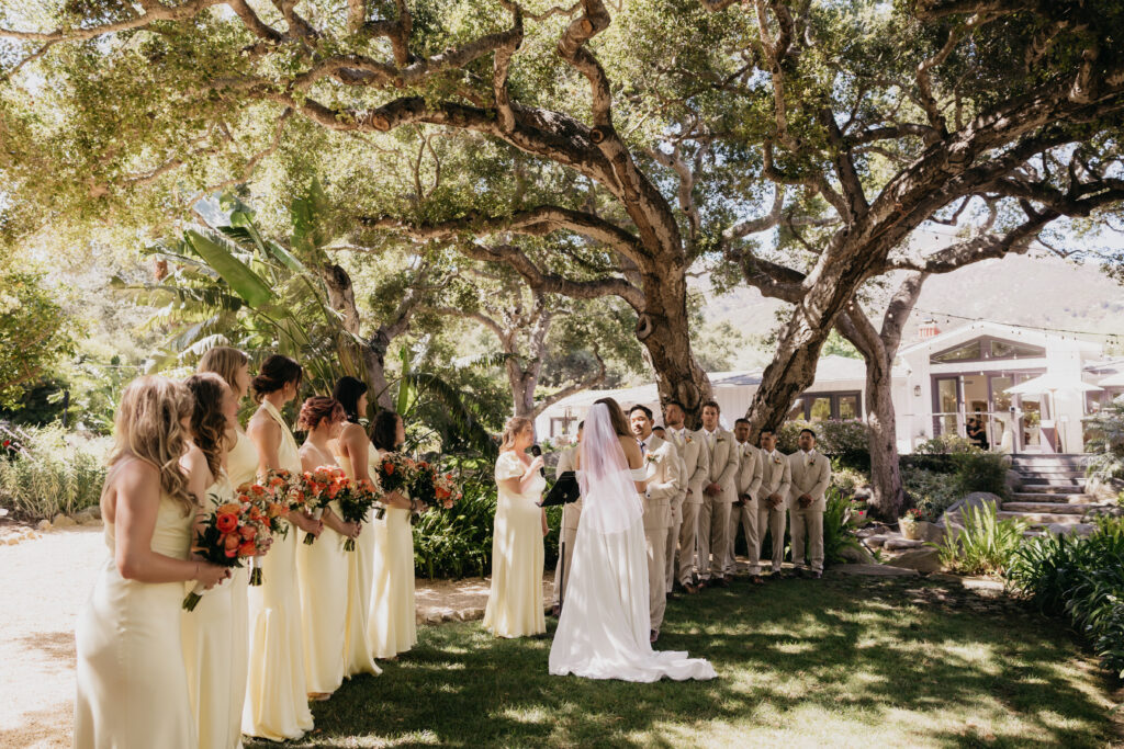 Bride and groom exchanging vows under oak trees at The Cole Home private estate wedding in Montecito.
