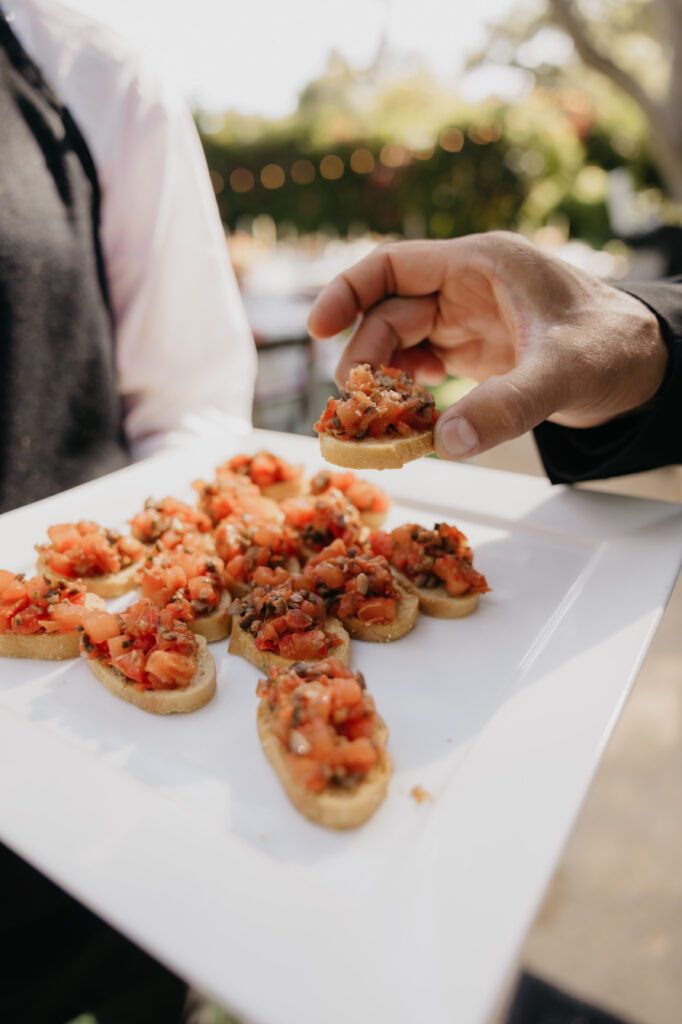 Tray of bruschetta appetizers being served during cocktail hour at a Montecito private estate wedding.