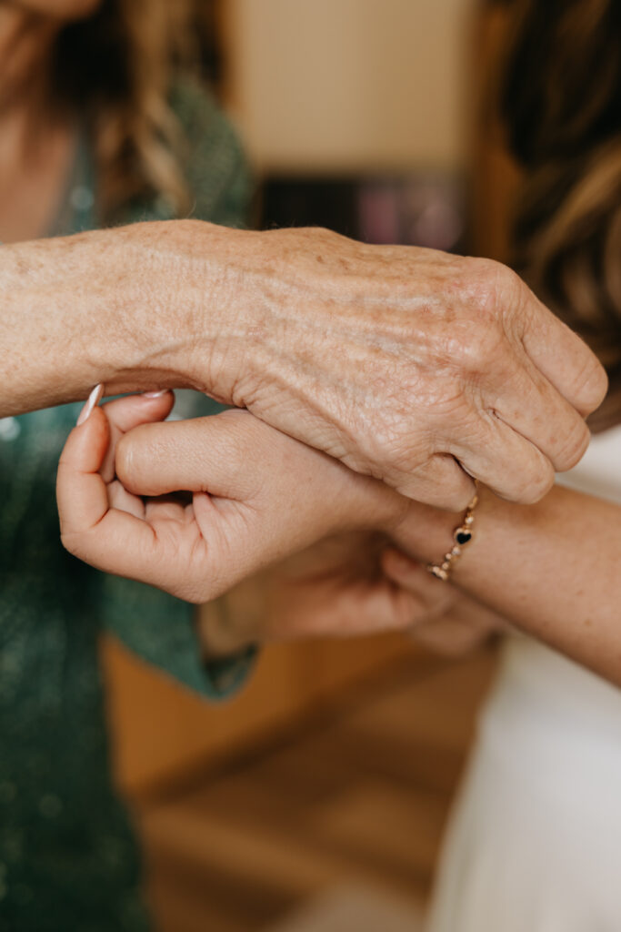 Close-up of a bride’s bracelet being fastened by a loved one before her Montecito private estate wedding.