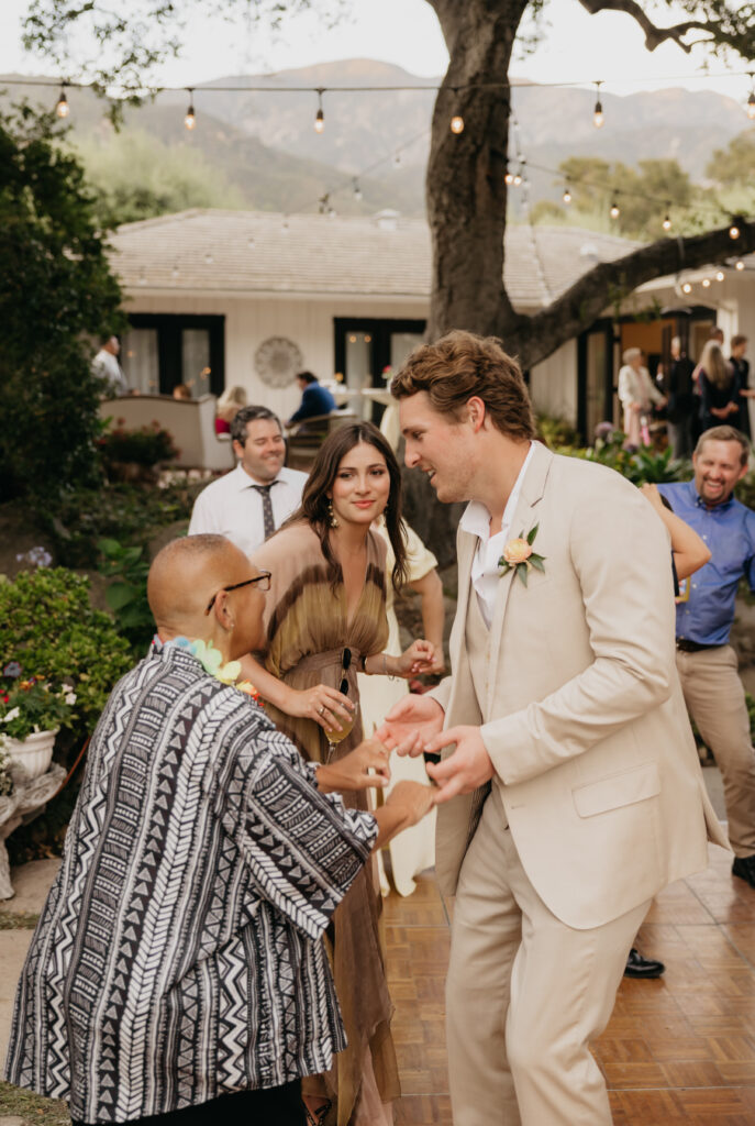 Wedding guests laughing and dancing together on the outdoor dance floor at The Cole Home in Montecito.