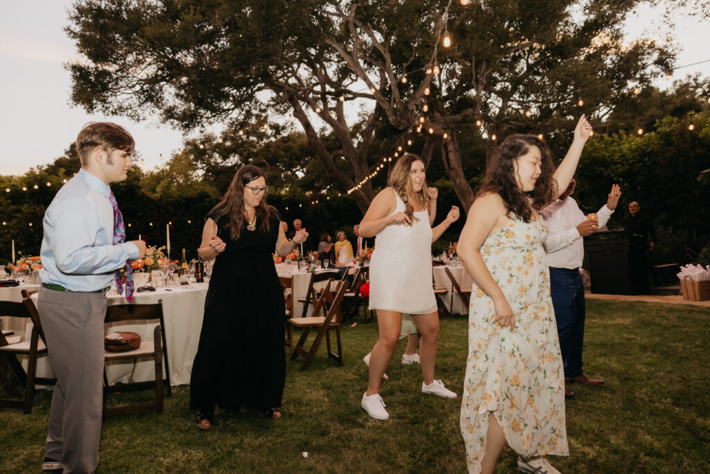 Guests dancing outdoors on the lawn during a Montecito wedding celebration.