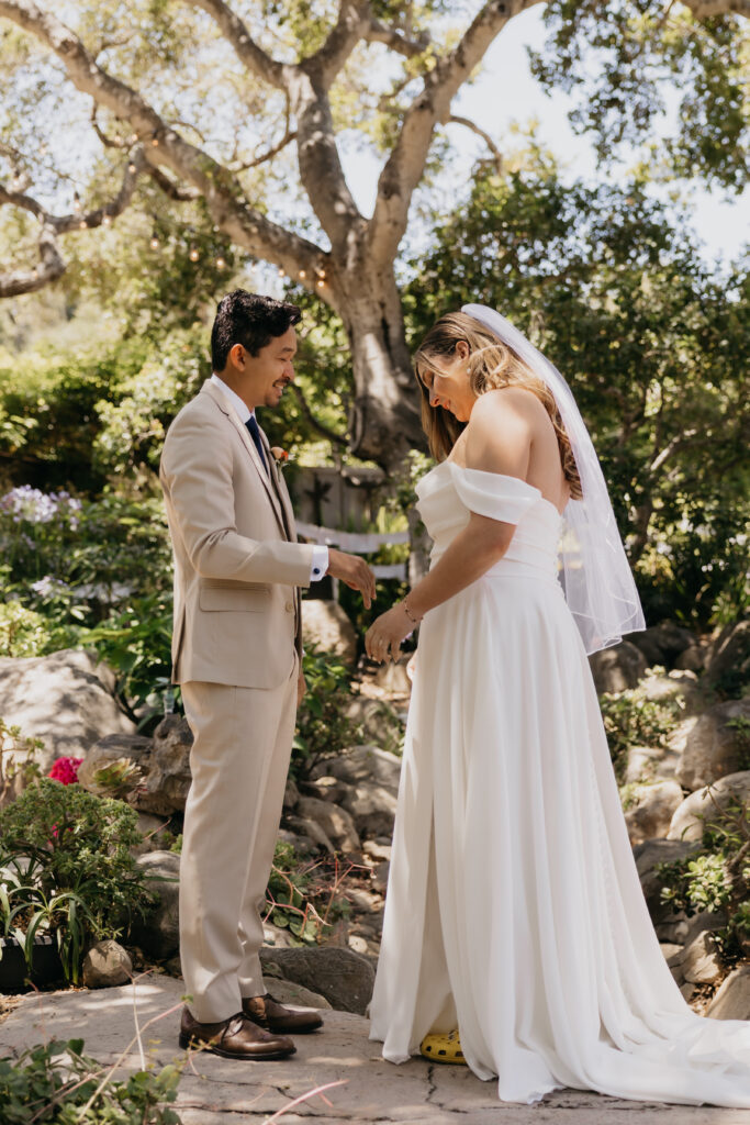 Groom and bride sharing an emotional moment while holding hands during their first look at a Montecito private estate wedding.