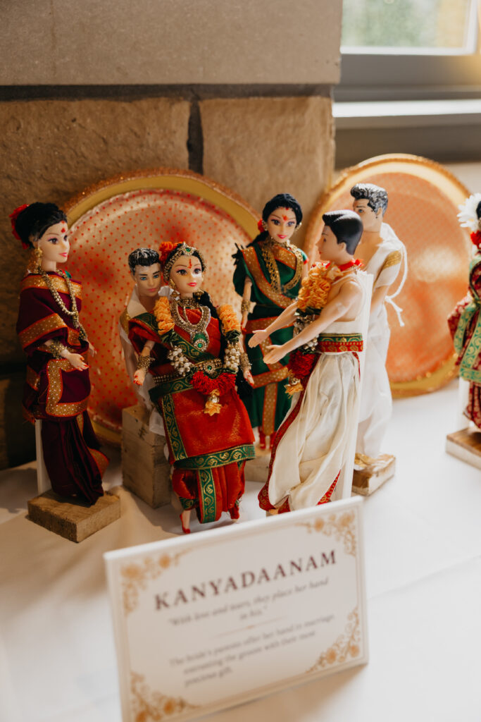 Traditional Indian wedding dolls dressed in sarees and dhotis, symbolizing bride, groom, and family during Var Pooja rituals