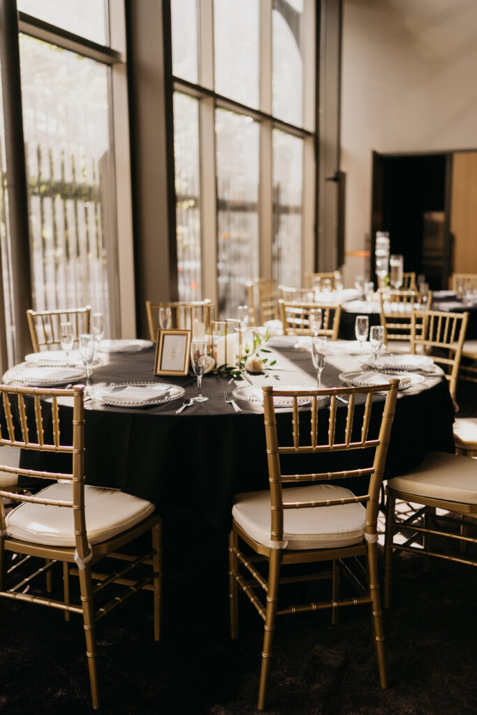 Wedding reception table with black linens, gold Chiavari chairs, and candlelit centerpiece at Renaissance Depot Minneapolis | Mycah Bain Photography.