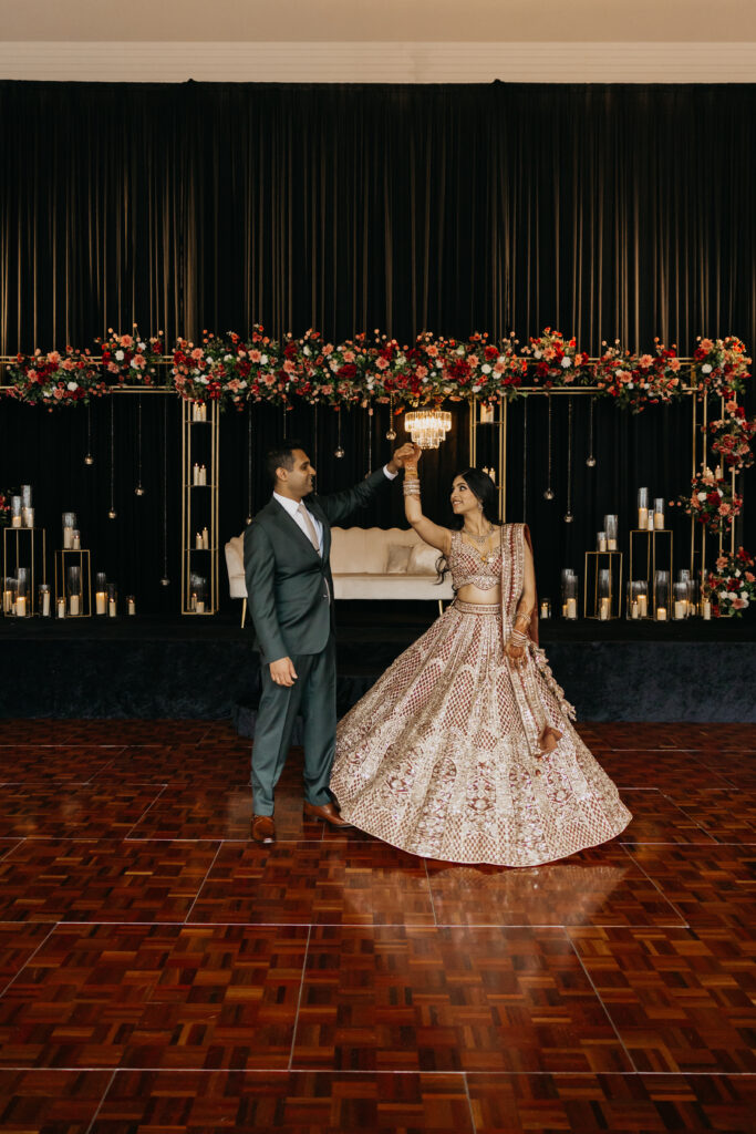 Groom twirls bride in shimmering lehenga during first dance at Renaissance Depot Indian wedding reception, captured by Mycah Bain Photography, traditional wedding photographer.