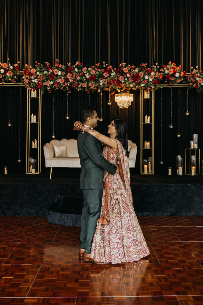 Bride and groom embrace on the dance floor under floral chandeliers and candlelit backdrop at Renaissance Depot Minneapolis, photographed by Mycah Bain Photography.