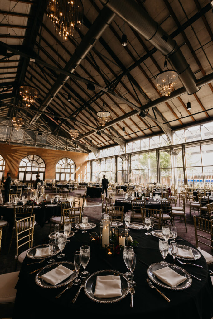 Wedding reception tables with black linens, gold chairs, and glassware at Renaissance Depot Minneapolis | Mycah Bain Photography.