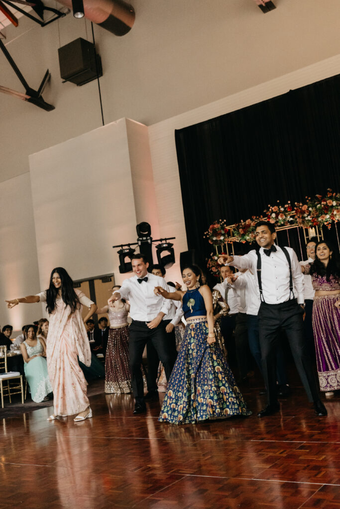Guests performing a lively dance together on the reception floor during Indian wedding celebration | Captured by Mycah Bain Photography, traditional wedding photographer.