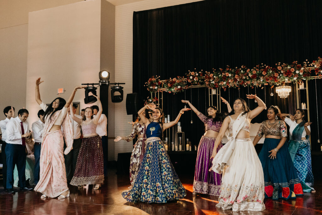 Wedding guests in colorful lehengas performing choreographed dance during Indian wedding reception at Renaissance Depot Minneapolis | Mycah Bain Photography.