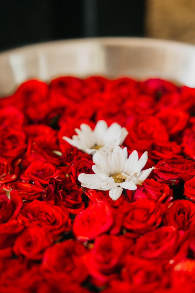 Floating white flowers arranged over a bed of red roses in a decorative bowl for Var Pooja ceremony