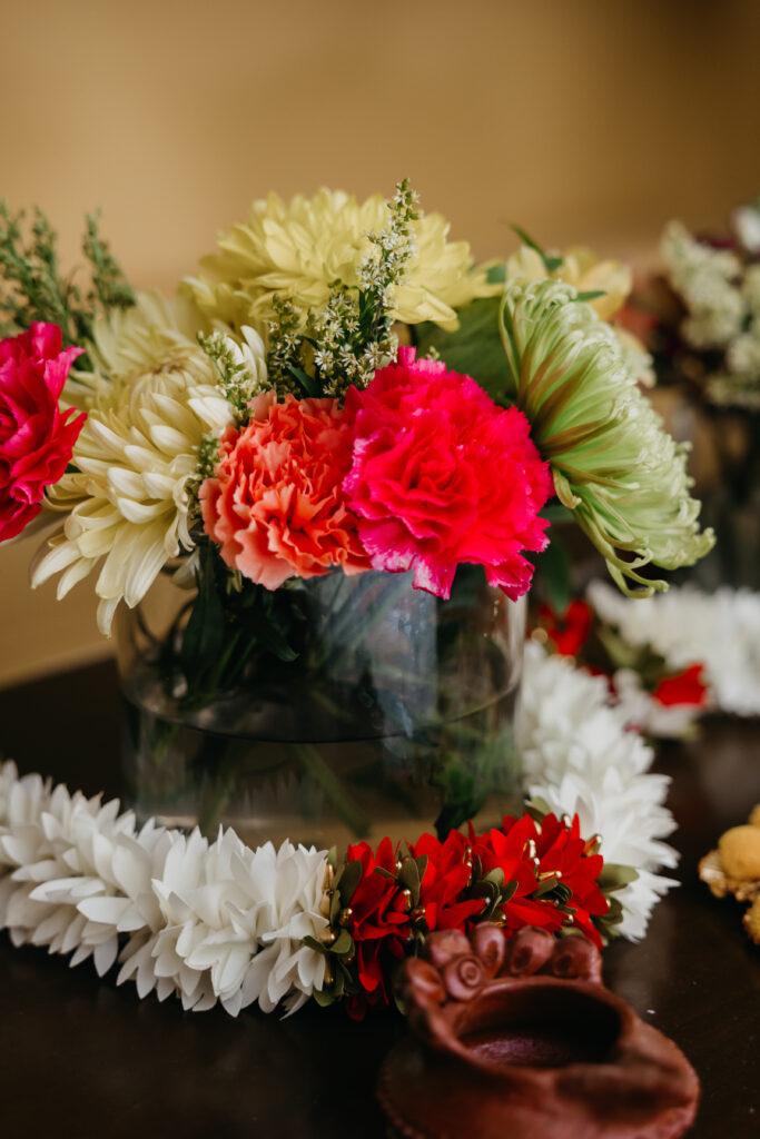 Bright floral arrangements of red, white, and green flowers prepared for Var Pooja wedding rituals