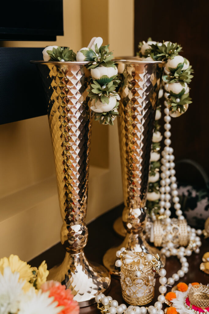 Golden vases adorned with jasmine garlands and fresh blooms for Indian wedding Var Pooja