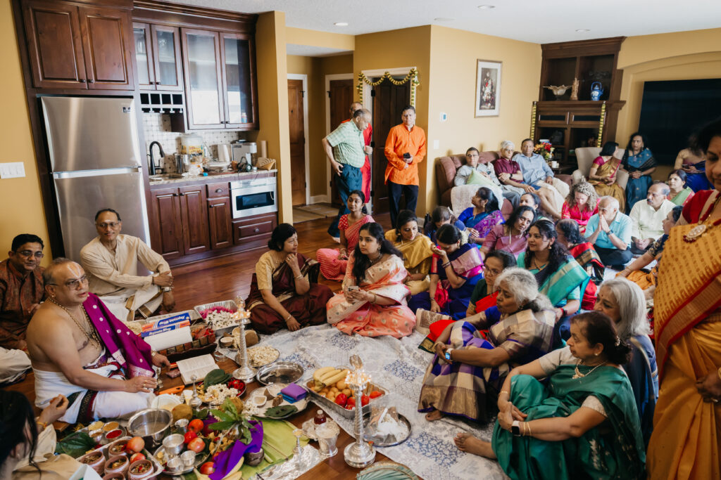 Family and guests seated on the floor in colorful sarees and attire, gathered for Var Pooja rituals