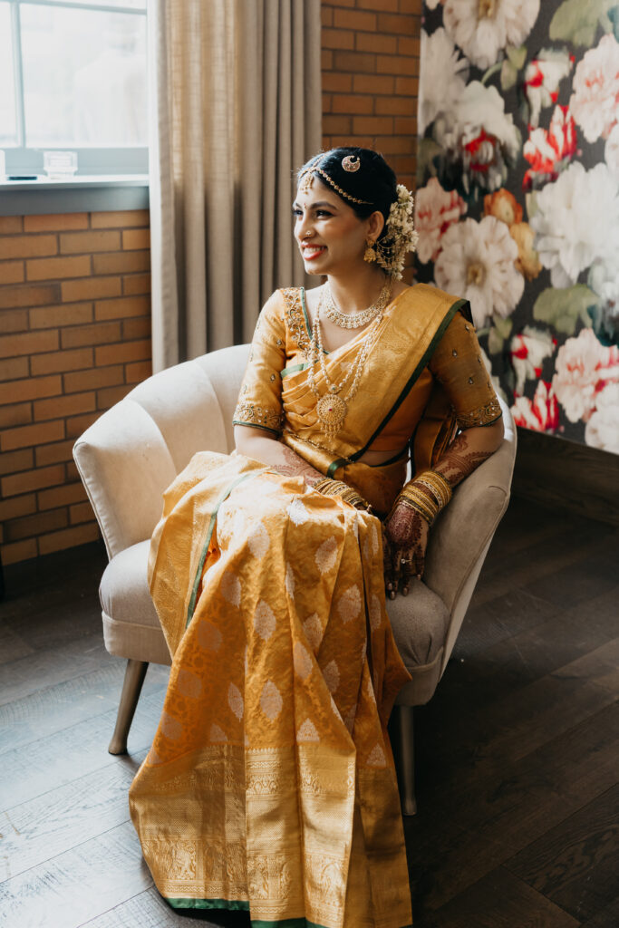 Smiling South Indian bride Apoorva in gold silk saree and jasmine flowers in her hair, ready for wedding ceremony