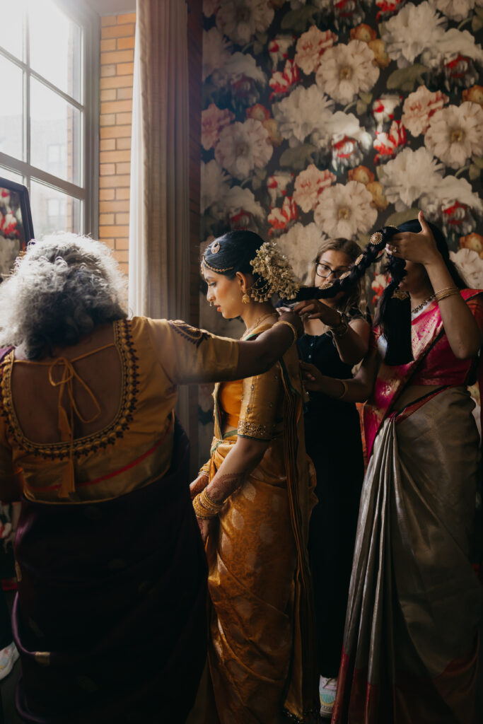 Bride Apoorva being dressed in silk saree with help from family members during Indian wedding preparations