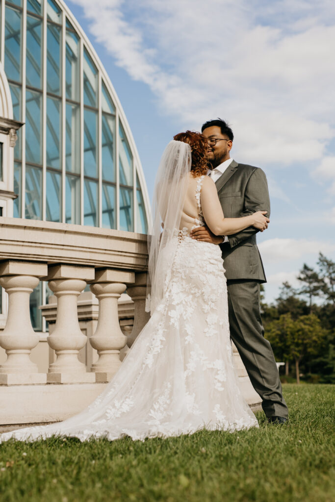 Romantic bride and groom kiss outside Como Park Conservatory wedding venue.