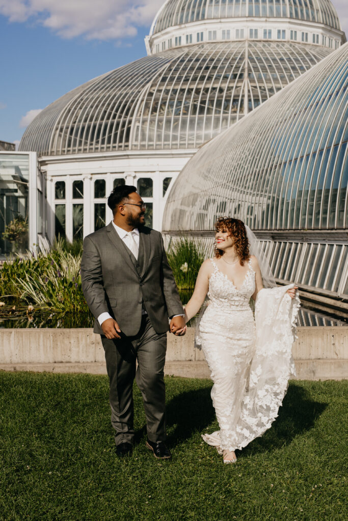 Bride and groom walking hand in hand outside Como Conservatory in Saint Paul, MN.