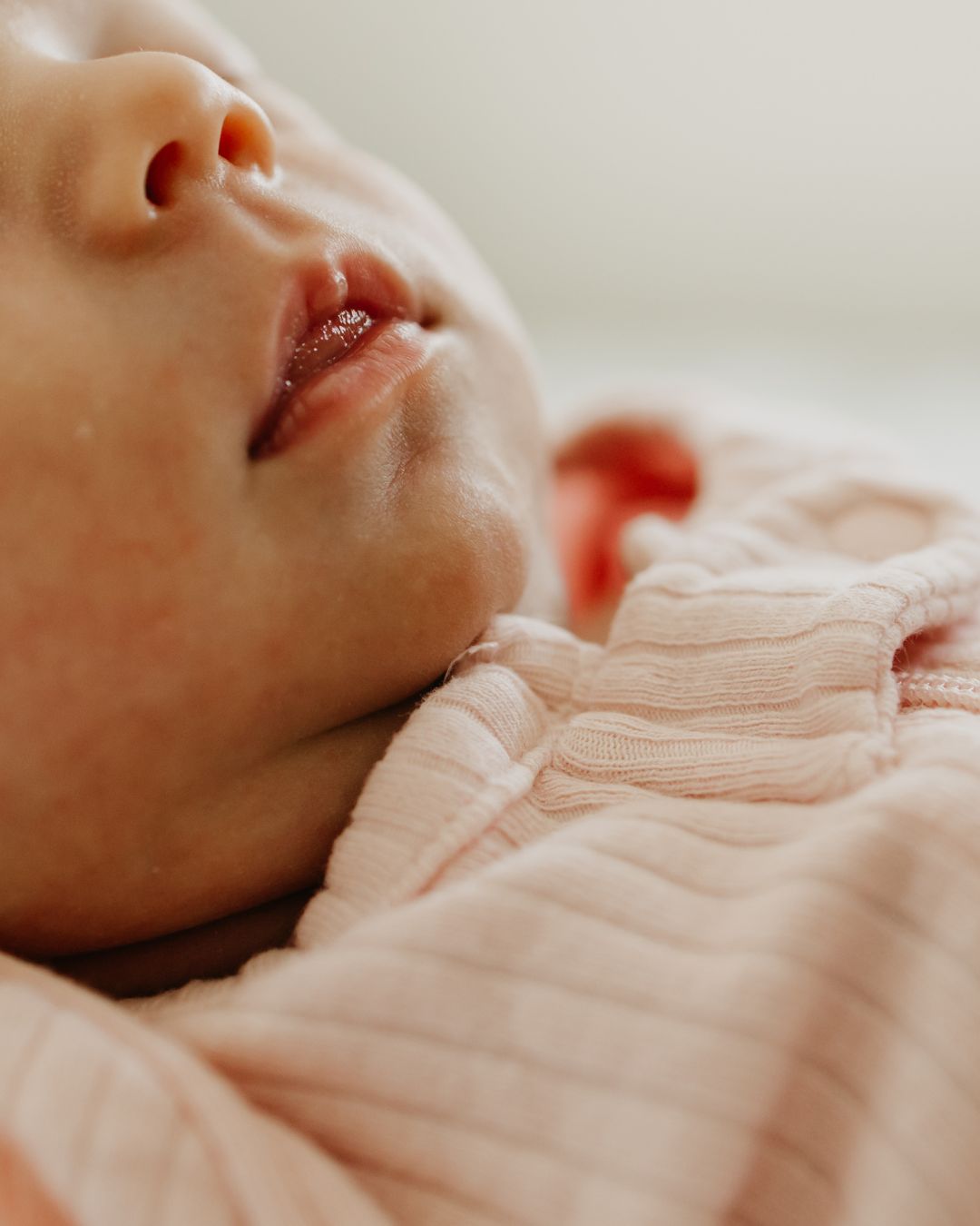 Close-up of a newborn baby’s lips and chin in soft natural light during an at-home photo session in Minneapolis.