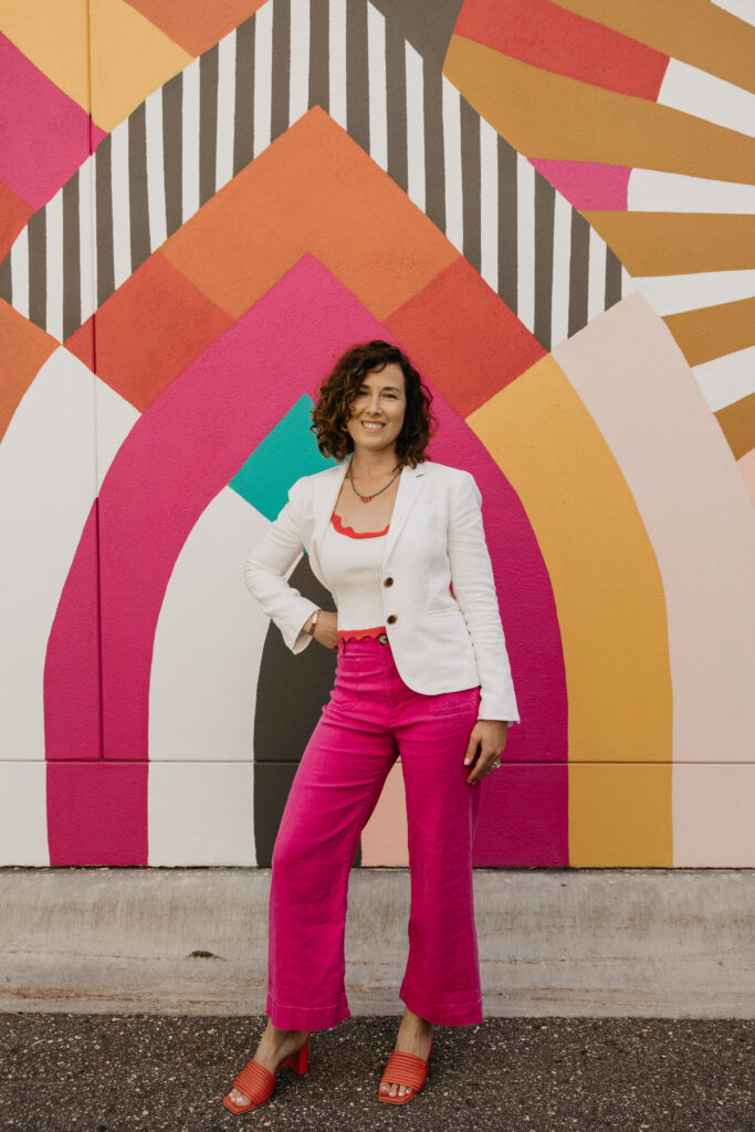 Anne Deanovic of Hot Mustard PR poses in front of a colorful mural near 50th & France during her brand photography session in Edina with Mycah Bain Photography.
