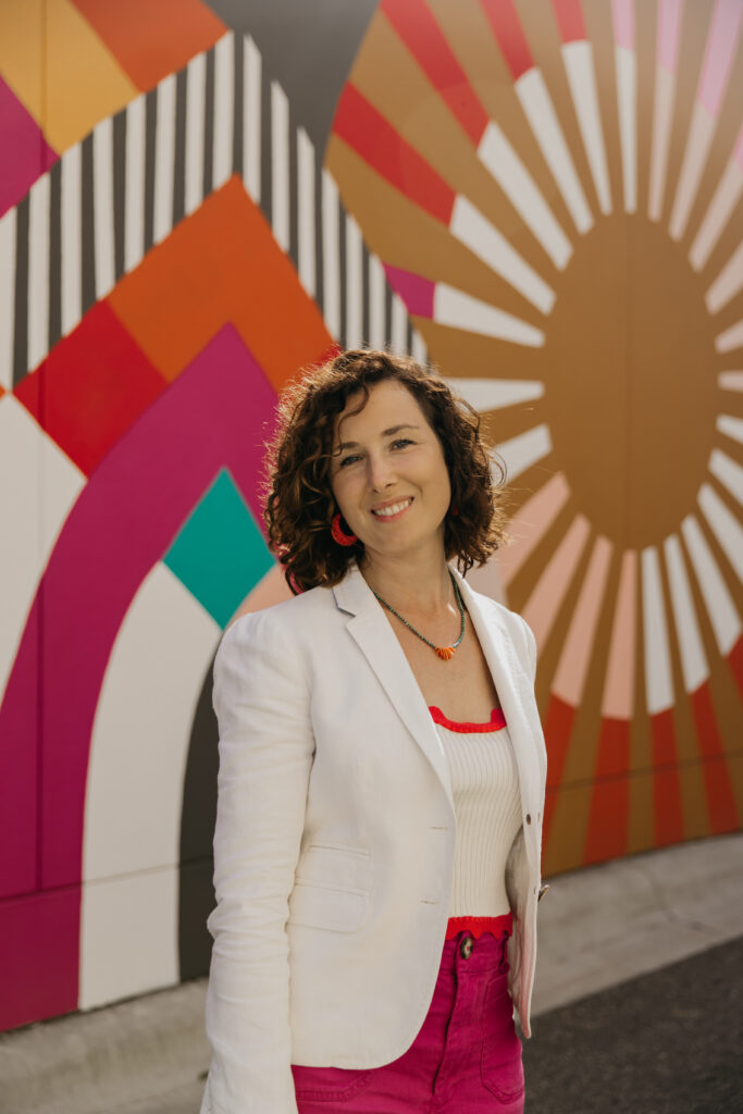Anne Deanovic of Hot Mustard PR poses in front of a colorful mural near 50th & France during her brand photography session in Edina with Mycah Bain Photography.