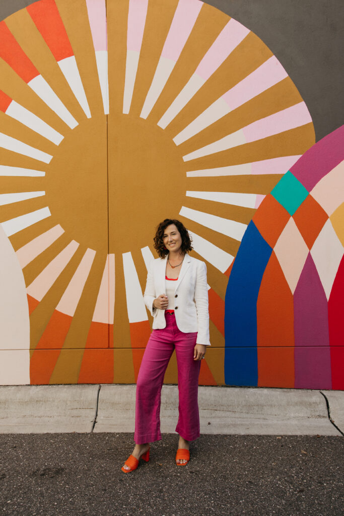Anne Deanovic of Hot Mustard PR poses in front of a colorful mural near 50th & France during her brand photography session in Edina with Mycah Bain Photography.