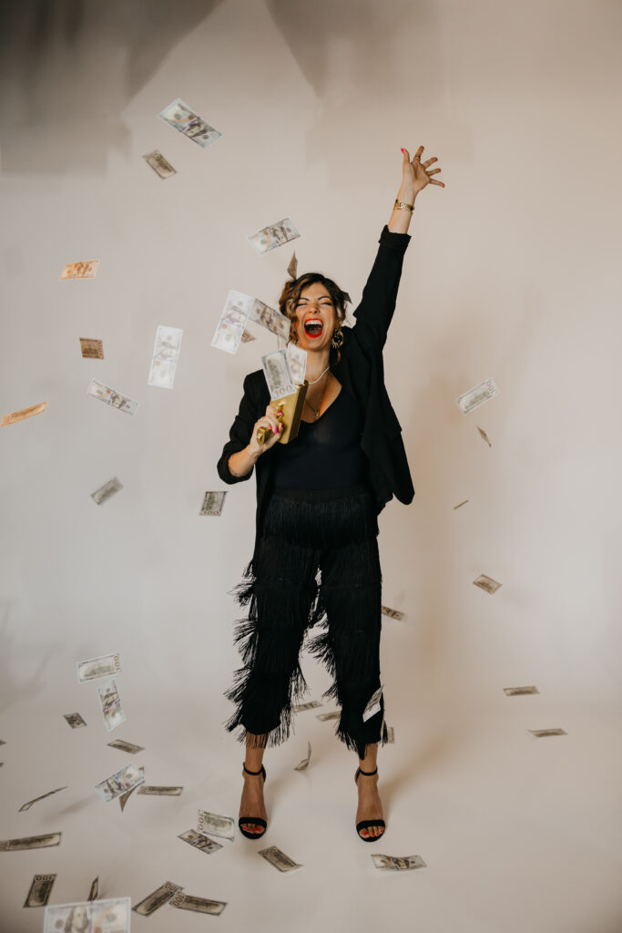 High-energy moment of Dr. Lauryn throwing money in the air, dressed in a black outfit, captured by Minneapolis Luxury Brand Photographer Mycah Bain.