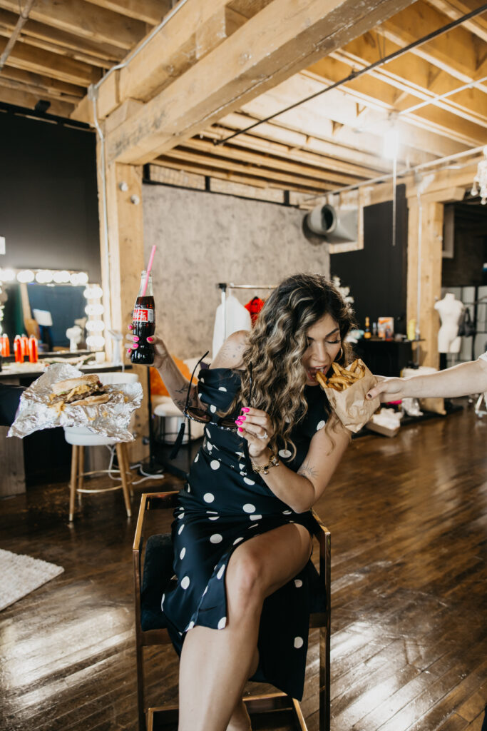Candid photo of Dr. Lauryn laughing while eating fries and holding a Coke during her luxury brand session at Studio One Minneapolis.