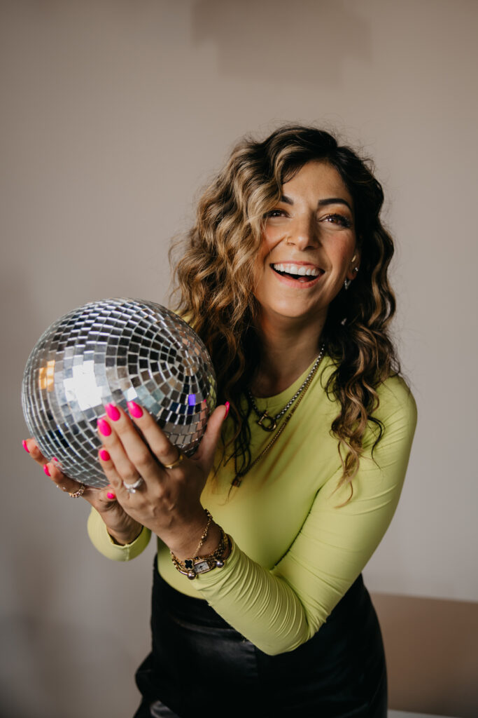 Playful image of Dr. Lauryn lying on the floor with glitter boots and microphone under an “On Air” sign during her brand photoshoot.