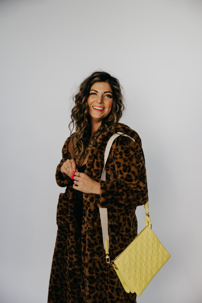 Lifestyle photo of Dr. Lauryn laughing on a red leather couch in a leopard print coat during her Minneapolis brand shoot.