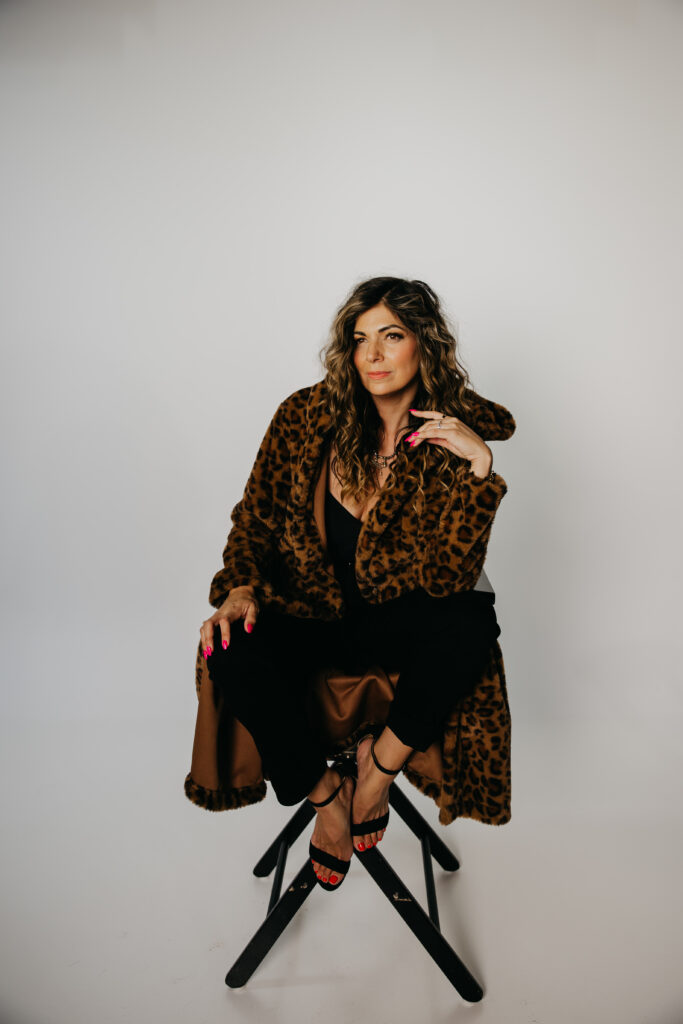 Lifestyle photo of Dr. Lauryn laughing on a red leather couch in a leopard print coat during her Minneapolis brand shoot.
