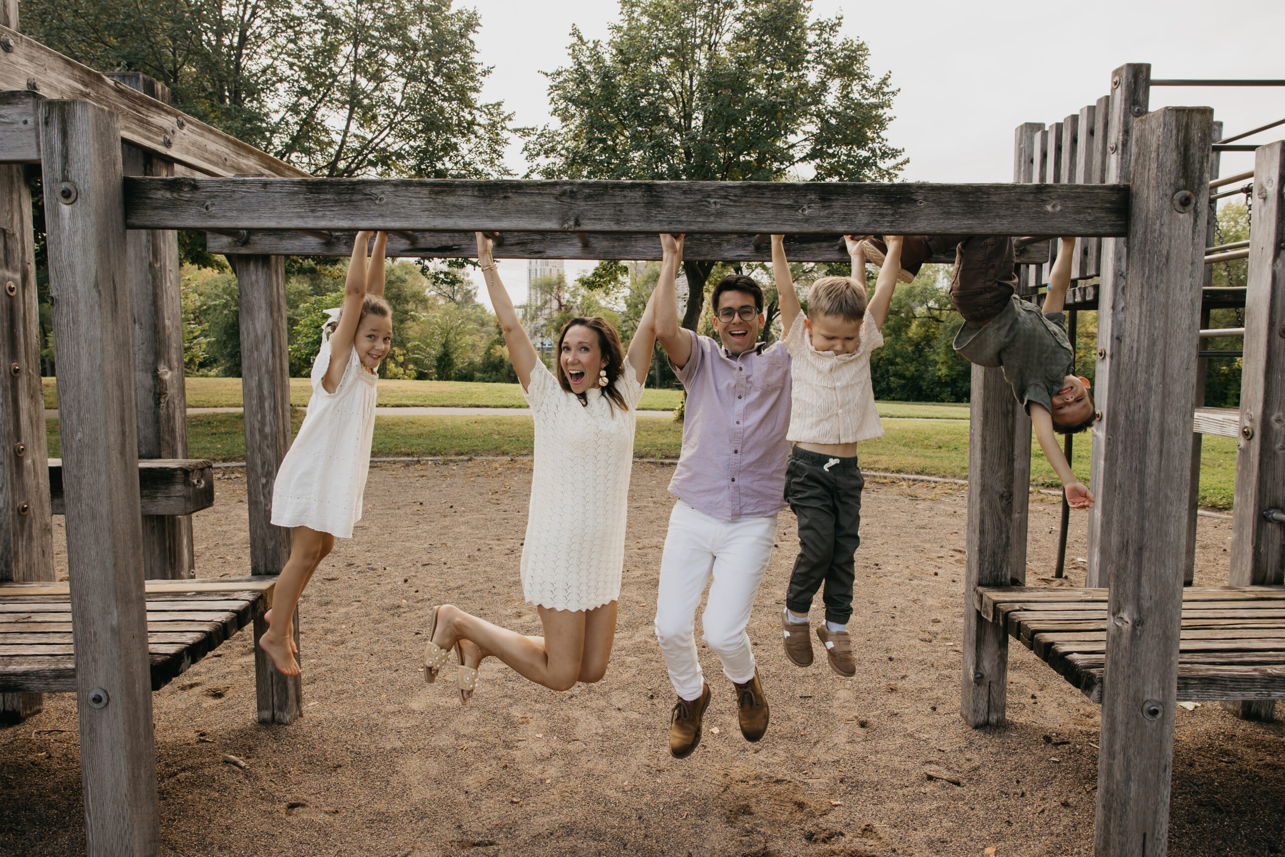 Family hanging and laughing together on a wooden playground at Boom Island Park in Minneapolis